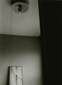 Black and white photograph of a ceiling lamp above a framed photograph