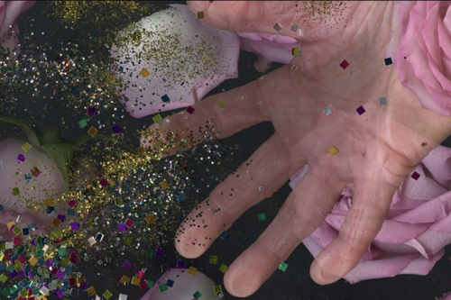 close up photo of a hand with open palm superimposed with pink roses and colored glitter