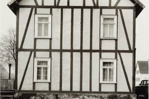 A black and white photograph of the facade of a house