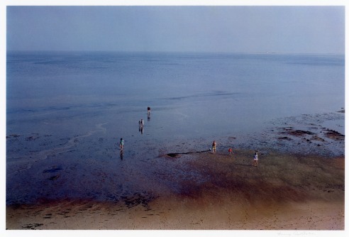 An aerial photograph of people on a beach in the evening