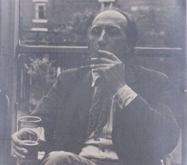A black and white photograph of a man smoking and drinking a beer in his chair on a porch