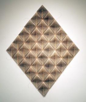 A diamond made up of smaller diamonds is hung on a white wall. 