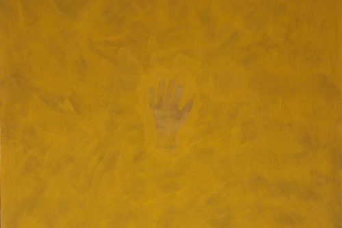 A hand can barely be seen in the middle of a vast dark yellow color field