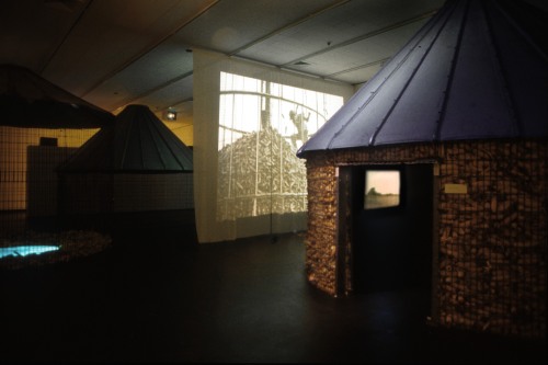 An installation of huts and a projected video