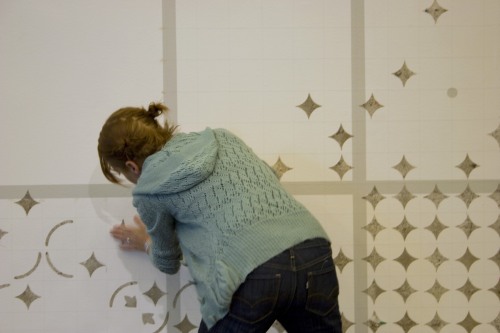 A woman installs stars on a gridded wall