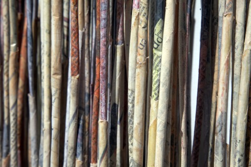 A colorful row of folded newspapers arranged so the folds form thin vertical lines across the image.