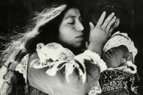Photograph of a woman holding a child, covering her face
