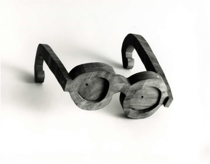 A pair of glasses with both frames and lenses made of a gray material sit on a white background